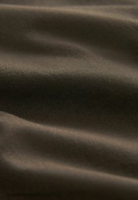 Tissu en coton marron avec une texture lisse, présentant des plis doux et un léger éclat. Le matériau est léger et durable.