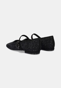 Bailarinas negras con adornos, con un empeine texturizado, que presentan tachuelas decorativas, doble correa y un tacón bajo cerrado. Adecuadas para diversas ocasiones.