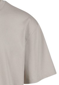 T-shirt en coton gris clair avec un col rond, des manches courtes et une texture lisse. L'ourlet est soigneusement cousu.