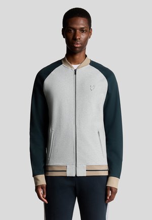 Grijze zip-up jack met donkergroene raglanmouwen en een beige kraag. Heeft zijzakken en gestreepte accenten aan de onderzoom.