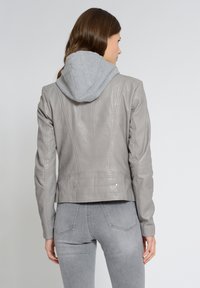 Grijze leren jack met een grijze capuchon. Heeft een getailleerd ontwerp, verticale naden en achterzakken met metallic accenten.