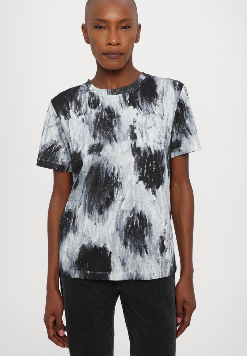 T-shirt abstrait noir et blanc avec des manches courtes, un col rond et une coupe décontractée. Le tissu a une texture douce et un minimum de détails de couture.