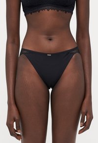 Crne bikini gaće od glatkog materijala, s čipkastim detaljem na pojasu i malim zlatnim logotipom sprijeda.