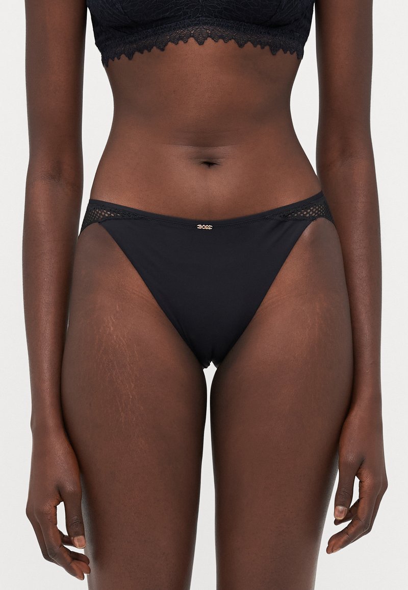Crne bikini gaće od glatkog materijala, s čipkastim detaljem na pojasu i malim zlatnim logotipom sprijeda.