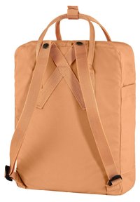 Sac à dos de couleur pêche avec des sangles en point de croix, en matériau textile, poignée supérieure et poche latérale. Texture lisse avec un design minimaliste.