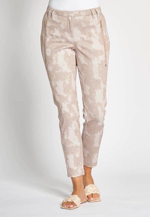 Light beige pants with a subtle camouflage pattern, featuring zip pockets and a tailored fit. Made from breathable fabric.