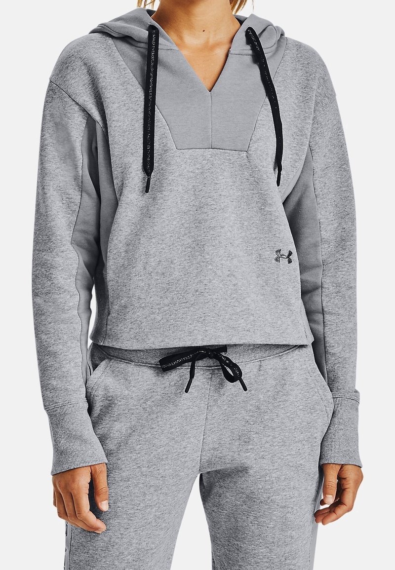 Donna che indossa un felpa leggera grigia di Under Armour con lacci neri e pantaloni della tuta grigi abbinati con vita regolabile.