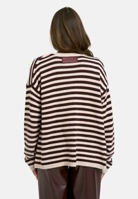 Gestreifter Pullover aus cremefarbener und dunkelbrauner Baumwollstrickware, mit entspanntem Schnitt, überschnittenen Schultern und einem "SOUL STUDIO" Lederetikett auf der Rückseite.