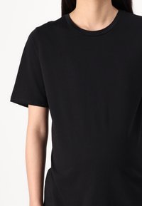 Black short-sleeve t-shirt made of cotton with a round neck. Features a smooth texture and a relaxed fit, with no visible patterns or accents.