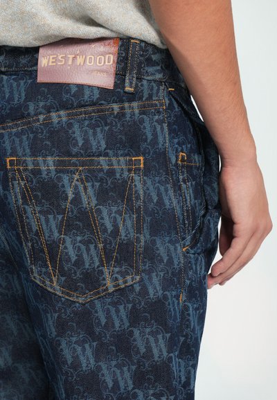 Blugi din denim cu un fundal albastru închis și un model subtil repetitiv. Cusătura portocalie accentuează buzunarele și eticheta de la talie.