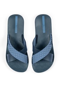Blaue Gummisandalen mit strukturierten Riemen, einer glatten Sohle und einem dezent gemusterten Fußbett. Das Markenlogo ist in Blau auf der Oberfläche gedruckt.
