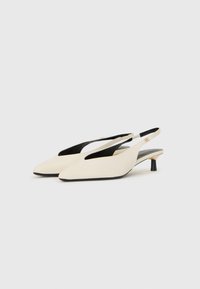 Korkeakantaiset slingback-kengät kahdessa värissä, kerma ja musta. Silkkinen synteettinen pinta, teräväkärkiset ja pienellä korolla. Ominaisuuksina leikkaukset lisäsuunnitteluominaisuutena.