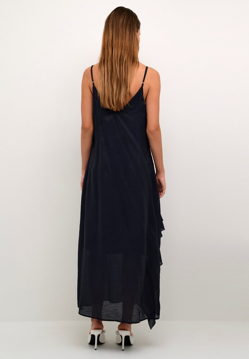 Marineblaues Maxikleid mit dünnen Spaghettiträgern, transparentem Stoff und einem rüschierten Saum. Der Rücken ist tief ausgeschnitten und zeigt ein luftiges und fließendes Design.