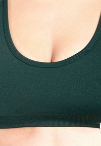 Mörkgrön stretchig bralette med rundad halsringning, ribbad struktur och slät yta. Inga synliga spännen eller mönster.