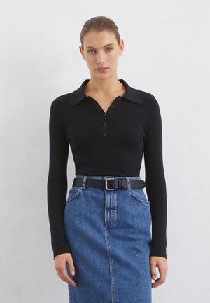Black long-sleeve polo shirt with a collared neck and button placket, paired with a high-waisted denim skirt and a black belt.