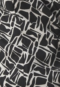 Schwarz-weiß gemusteter Stoff mit abstrakten Formen und unterschiedlichen Texturen, mit einem weichen, leicht zerknitterten Finish.