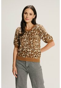 Sweter w panterkę w kolorze brązowym, wykonany z miękkiego materiału, z krótkimi bufkami i prążkowanym dołem. Połączony z szarymi dżinsami o wysokim stanie.