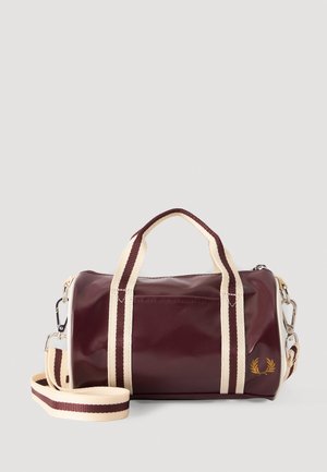 Bolsa de lona pequeña color granate con asas a rayas crema y marrón y correa de hombro ajustable, con logo de corona de laurel dorada.