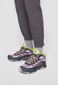 Chaussures de randonnée violettes et grises avec une tige texturée, des accents jaunes et des lacets noirs ; dotées d'une semelle robuste offrant une bonne adhérence.