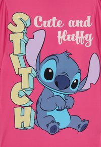 Svijetlo ružičasta tkanina s crtanom plavom vanzemaljcem koji ima velike uši, tekstom na kojem piše "Sladak i pahuljast", i podebljanim žutim slovima koja spell-uju "ŠIVI".