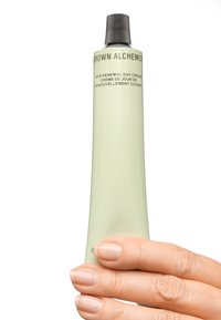 Lichtgroene, cilinderachtige tube van de "Grown Alchemist" huidvernieuwende dagcrème met zwarte dop en tekstdetails op het oppervlak.