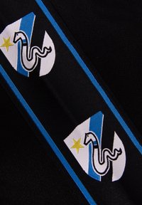 Zwarte stof heeft een geborduurd ontwerp met een witte driehoek, lichtblauwe accenten, een slangafbeelding en een gele ster.