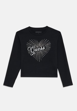 Top corto de manga larga negro con un diseño de corazón brillante que lleva la palabra "Guess" en una fuente cursiva, hecho de suave algodón orgánico.