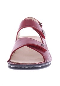 Rote Leder-Sandale mit breiten Kreuzriemen, einer verstellbaren Schnalle, einer gepolsterten Innensohle und einer strukturierten schwarzen Sohle.