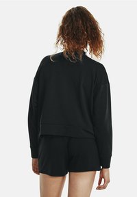 Schwarzes, kurzes Sweatshirt mit einer lockeren Passform und geripptem Saum, kombiniert mit passenden schwarzen Shorts. Weicher Stoff und minimalistisches Design.