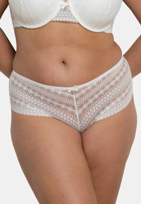 Culotte en dentelle blanche avec un motif géométrique en diamants, dotée d'une taille lisse et d'un nœud décoratif à l'avant.