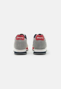 Sneakers grigi e bianchi con accenti rossi e blu navy. Tacco in suede e parte superiore in rete, caratterizzati da una suola spessa con una striscia blu. Logo sul tallone.