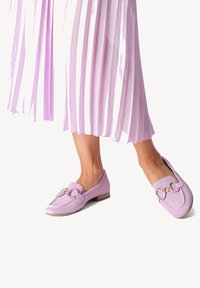 Lavendelkleurige loafers van gestructureerde stof, met een strik aan de voorkant en goudkleurige accenten, en een laag hakje voor comfort.