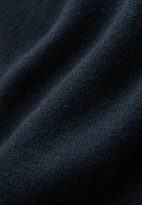 Ciemnogranatowa tkanina o miękkiej, puszystej fakturze i subtelnych fałdach tworzących delikatne cienie i głębię.