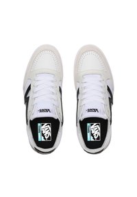 Zapatillas Blancas Vans con acentos negros, materiales de cuero y ante, caja de puntera perforada, cordones y logotipo en la lengüeta y en la plantilla.