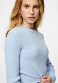 Gaiši zils ribota garām piedurknēm blūze ar apaļu kaklu. Mīksta auduma tekstūra, pieguļoša forma, ar smalkiem šuvuma elementiem.