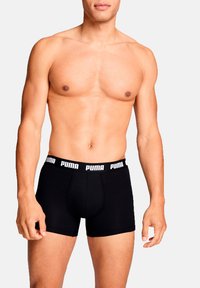 Schwarze Baumwoll-Boxershorts mit einem weißen elastischen Bund, der das "PUMA"-Logo trägt. Das Design ist figurbetont und glatt strukturiert.