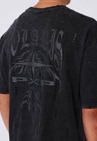 Zwarte oversized t-shirt met gescheurde gaten, met een donker grafisch ontwerp van "POLARIS" en "PXP" op de achterkant. Gemaakt van zachte stof.