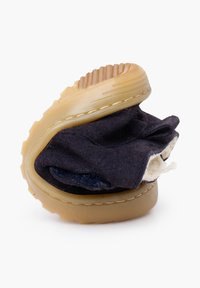 Boty z námořnické modré tkaniny s flexibilním tělem, texturovanou gumovou podrážkou a minimálním šitím. Boty jsou přeložené a stlačené.