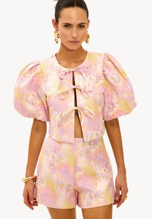 Conjunto de dos piezas floral que incluye un top corto de manga corta con lazos y mangas abullonadas, junto con unos pantalones cortos de cintura alta a juego, en tonos pastel de rosa y amarillo.