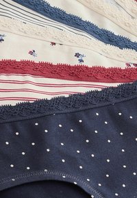 Pile de cinq sous-vêtements féminins avec bordures en dentelle, présentant des motifs tels que des pois, des rayures et de petites fleurs en tons bleu, blanc et rouge.