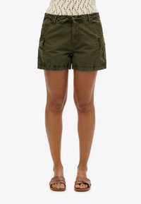 Shorts cargo vert olive avec poches latérales, taille élastique, et coupe décontractée. Tissu doux avec un léger éclat, idéal pour une tenue décontractée en été.