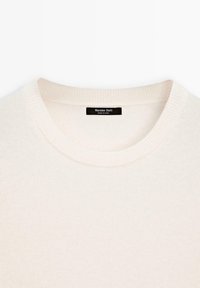 Krämfärgad stickad tröja med rund halsringning och ribbad kant. Har en subtil textur och en svart etikett med "Massimo Dutti" baktill.