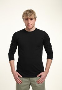 Černé dlouhé tričko s dlouhým rukávem, ve fitted designu, vyrobené z měkké bavlny, s kulatým výstřihem a hladkým povrchem.