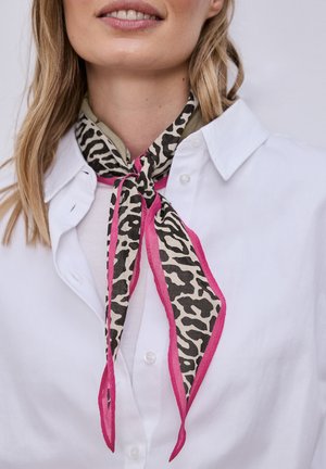 Femme portant une chemise blanche à col et une écharpe à imprimé animalier avec une bordure rose autour du cou