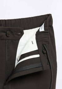 Ciemnobrązowe spodnie z zapięciem na guzik i zamek, z białą podszewką wewnętrzną oraz kontrastującym paskiem na pasie.