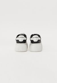 Sorte og hvite plattform-sneakers med ribbede såler, med en blank finish og merkede hæl-accents. Justerbart snøringdesign foran.
