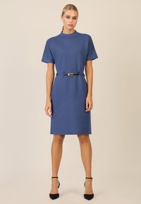 Abito in maglia blu con maniche corte, scollatura alta e una cintura nera con fibbia dorata. Texture morbida e design fino al ginocchio.