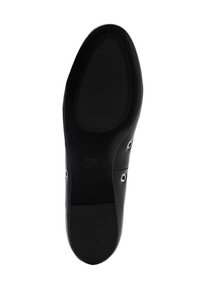 Schwarze Schuhsohle mit strukturierten Gummibereich, die eine glatte Kante und runde Lochakzente an den Seiten für zusätzliche Details aufweist.