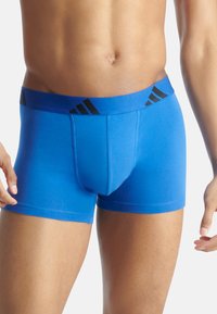 Modré pánské boxerky s přiléhavým střihem, látkovým pasem s černými akcenty a hladkou, elastickou texturou.