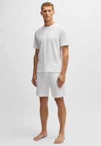 Witte katoenen t-shirt en short set, met een ronde halslijn, korte mouwen en een relaxte pasvorm met subtiele textuur. Geen zichtbare patronen of hardware.